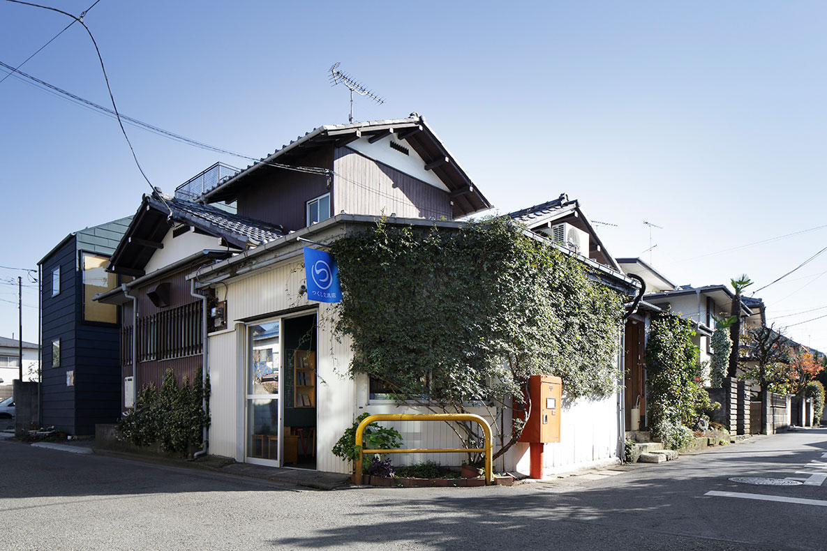 JR中央線国立駅北口から歩いて20分ほどの住宅街にあった「つくし文具店」の店構え。白い壁にツタが絡み、青いのれんが見える。